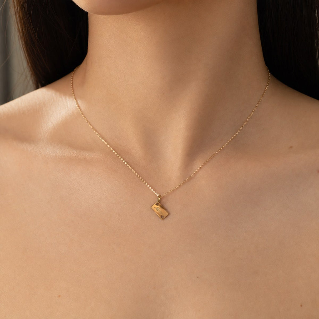 14K solid gold love tag pendant worn on a fine chain