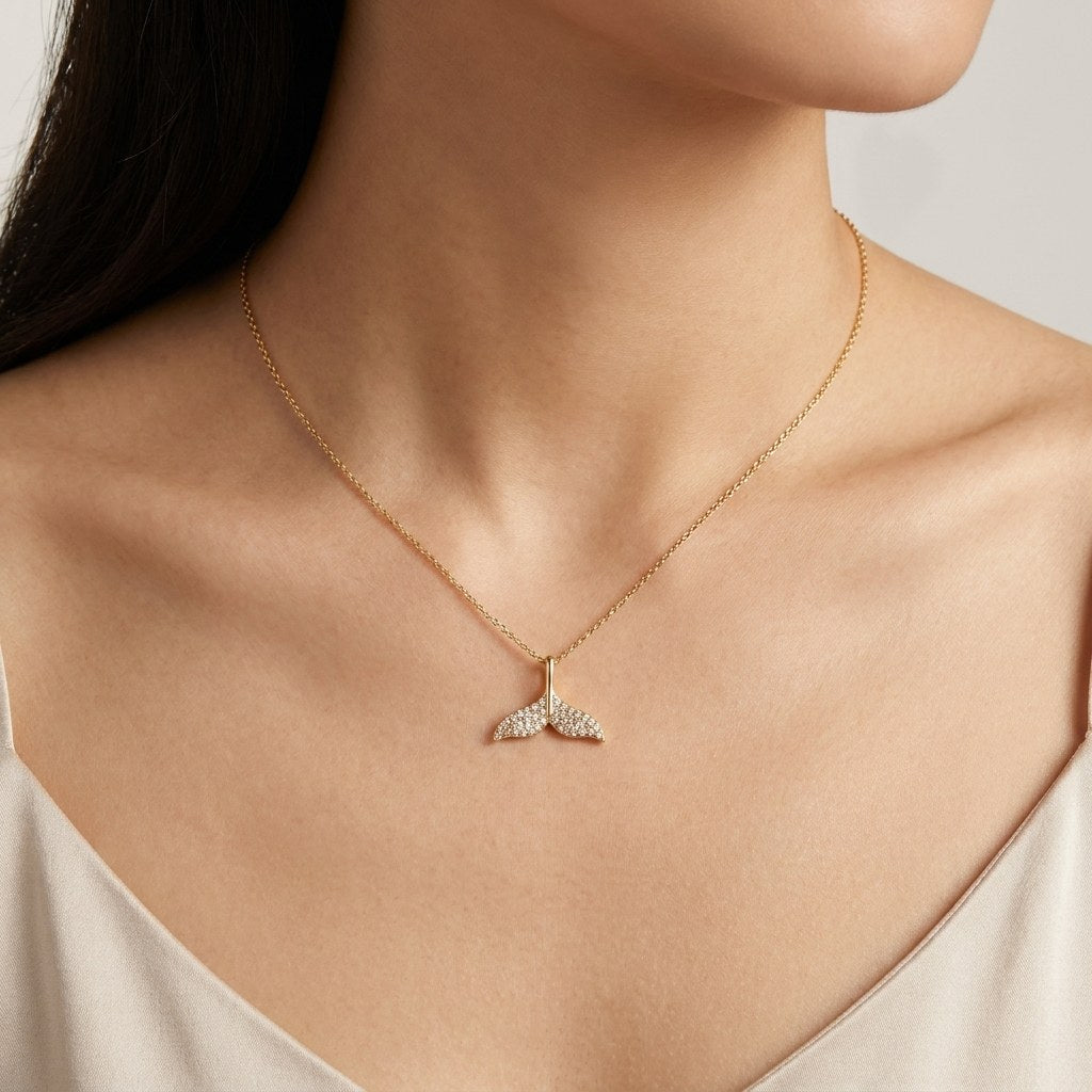 14K solid gold pavé whale tail pendant worn on a fine chain