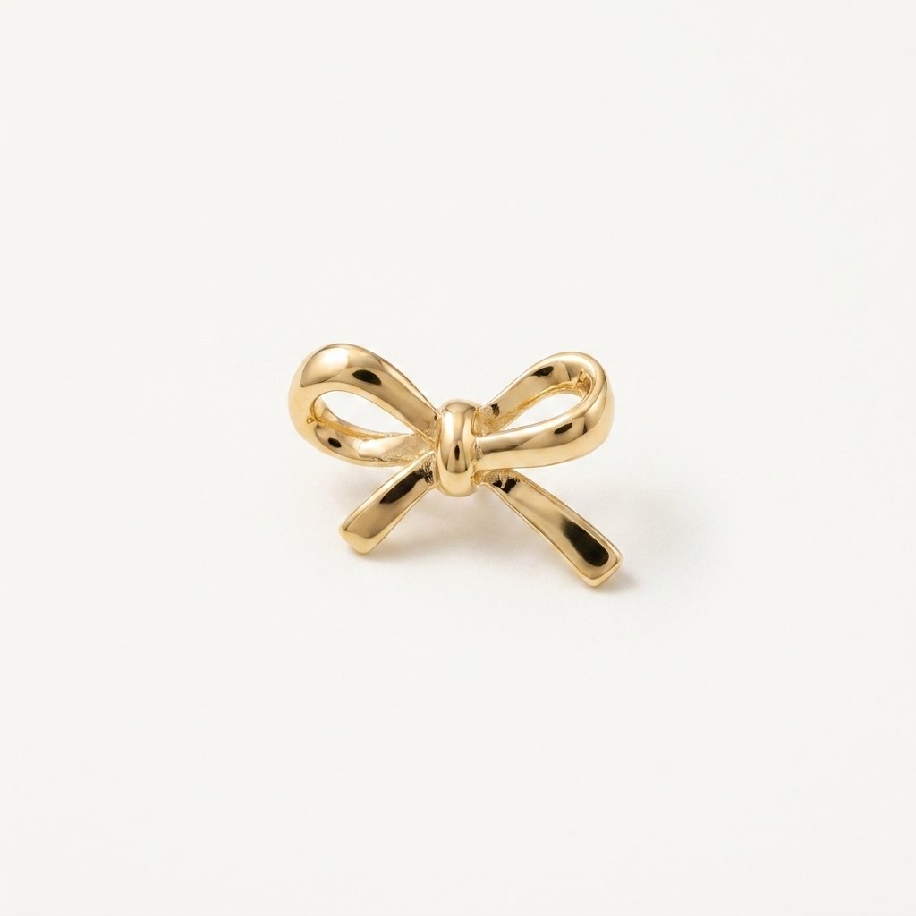 14K solid gold ribbon bow pendant on a warm ivory background