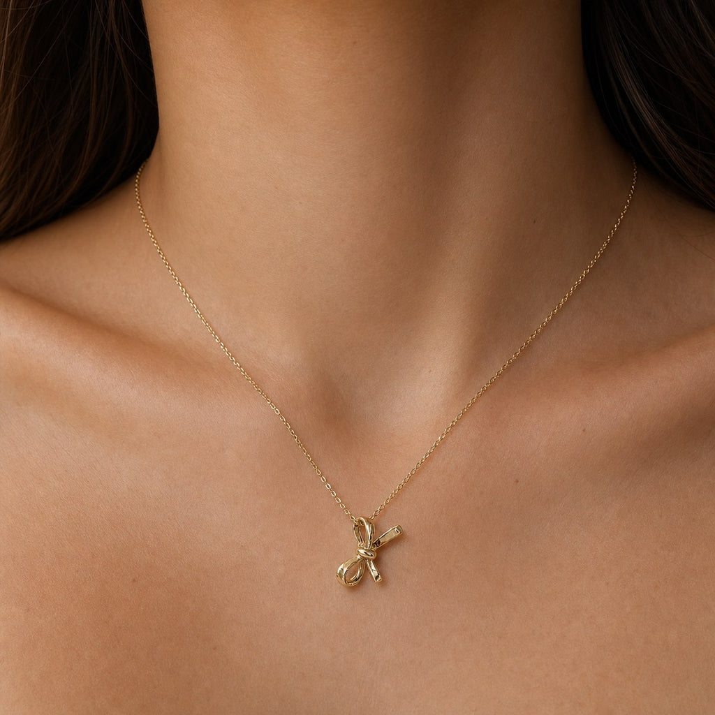 14K solid gold ribbon bow pendant worn on a fine chain