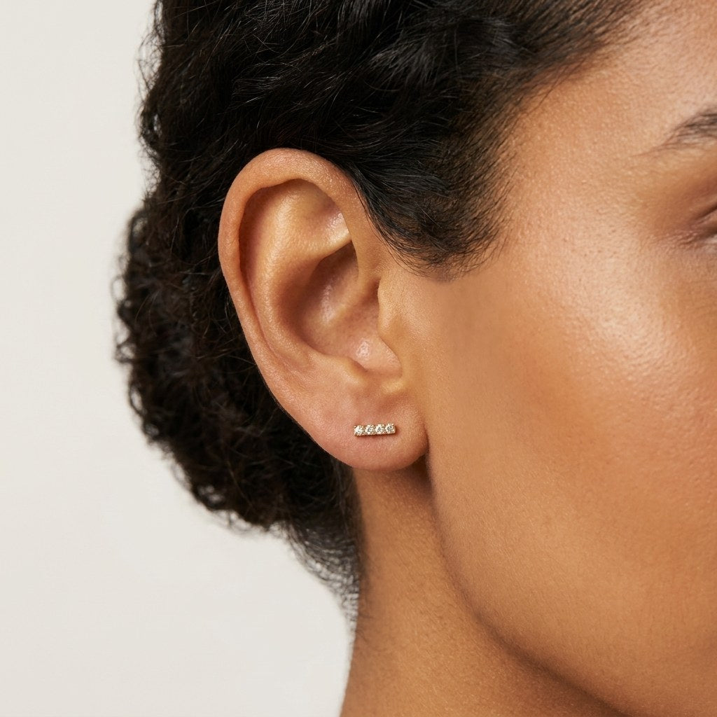 14K solid gold pave bar stud earrings worn on an ear