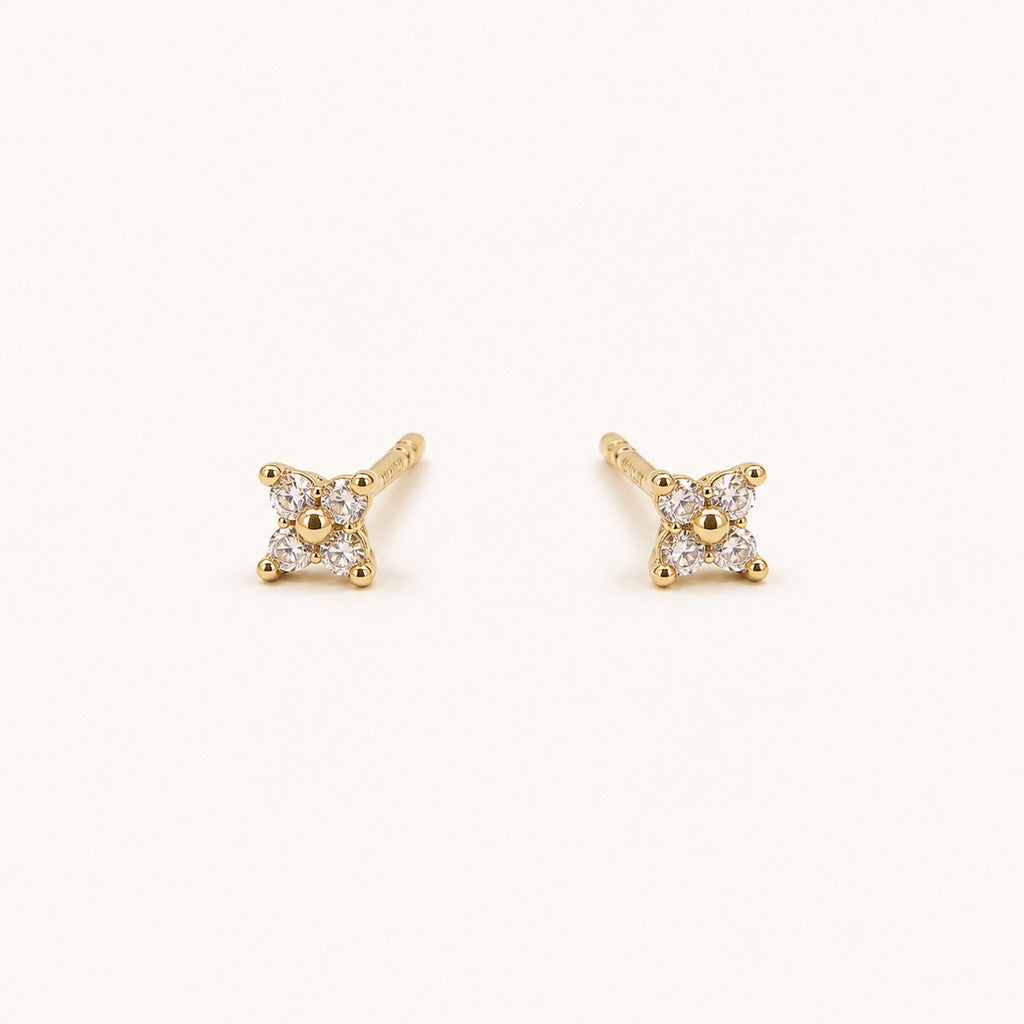 14K solid gold crystal floral star stud earrings on a warm ivory background