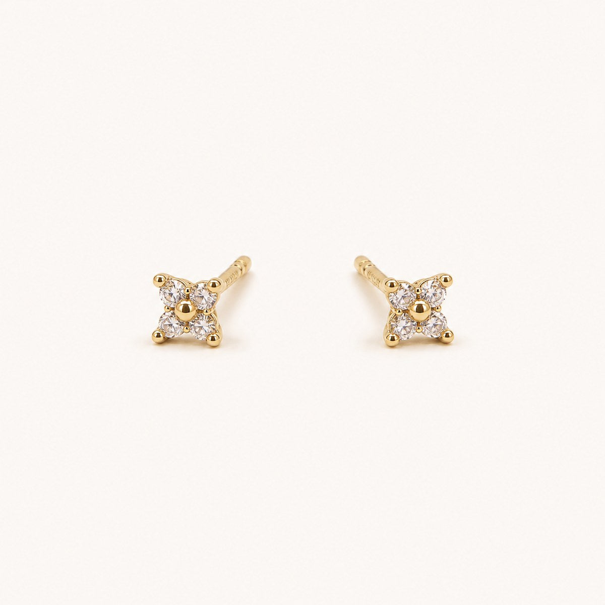 14K solid gold crystal floral star stud earrings on a warm ivory background