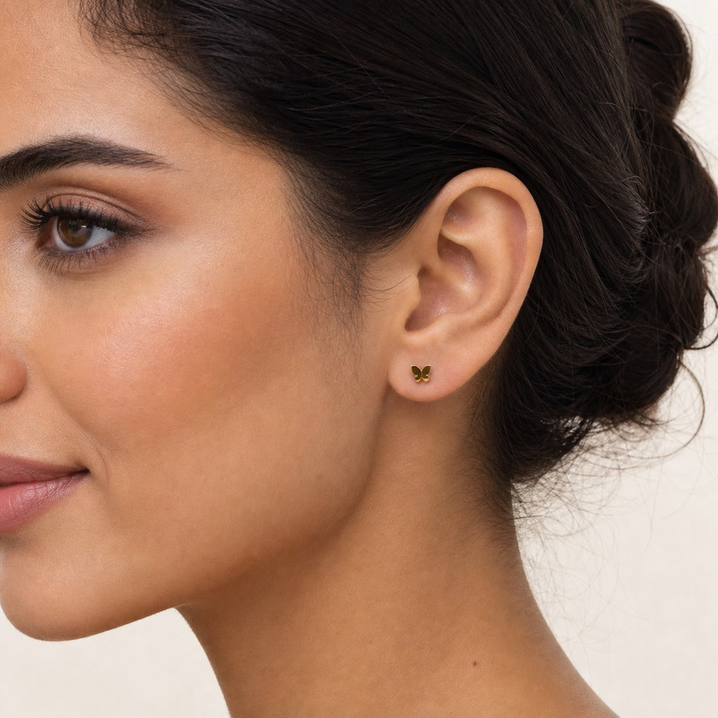 14K solid gold polished butterfly stud earrings worn on an ear