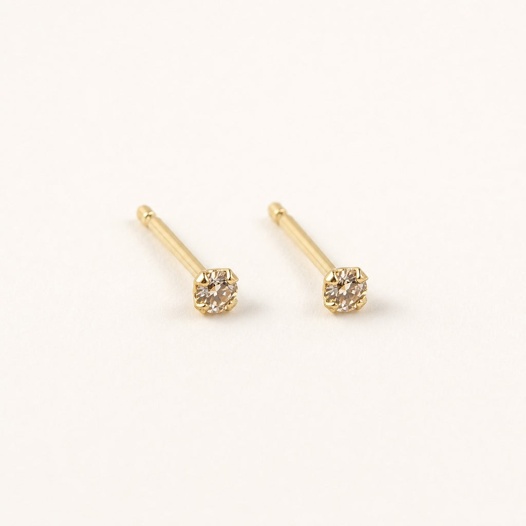 14K solid gold petite bezel solitaire stud earrings on a warm ivory background