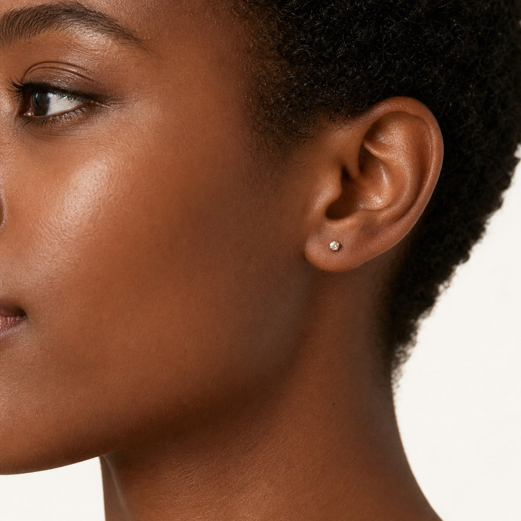 14K solid gold petite bezel solitaire stud earrings worn on an ear