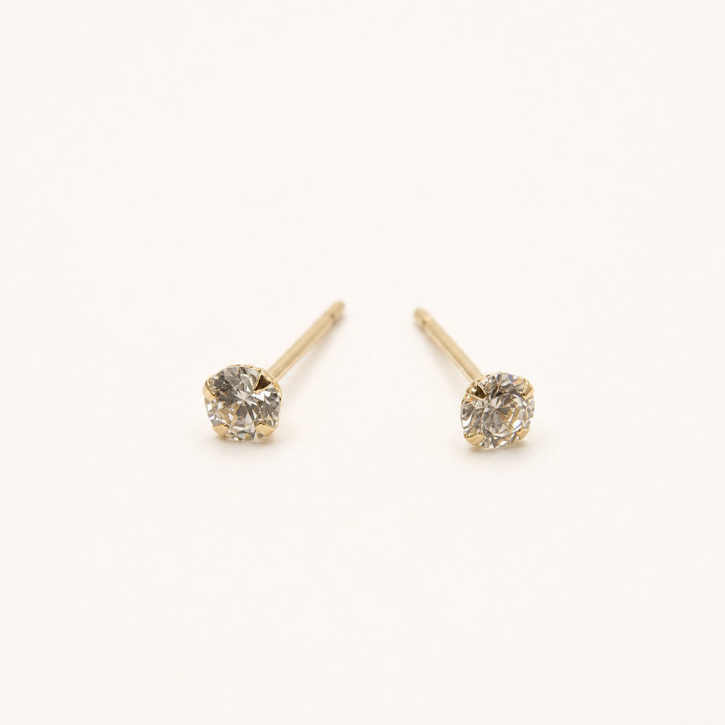 14K solid gold petite round solitaire stud earrings on a warm ivory background