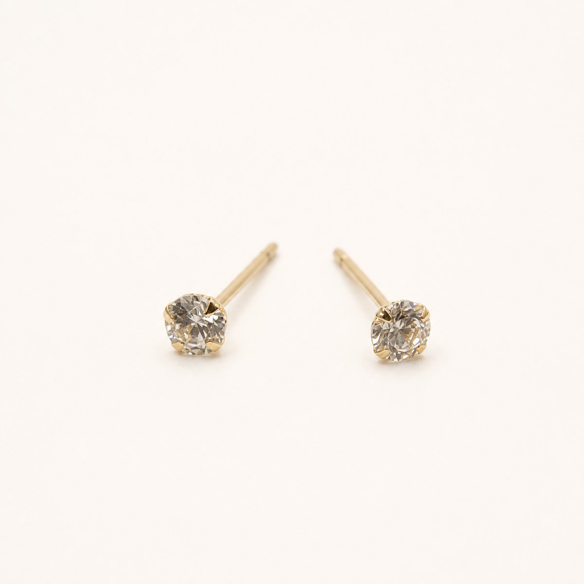 14K solid gold petite round solitaire stud earrings on a warm ivory background