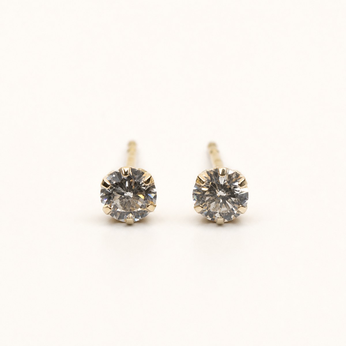 14K solid gold classic round solitaire stud earrings on a warm ivory background