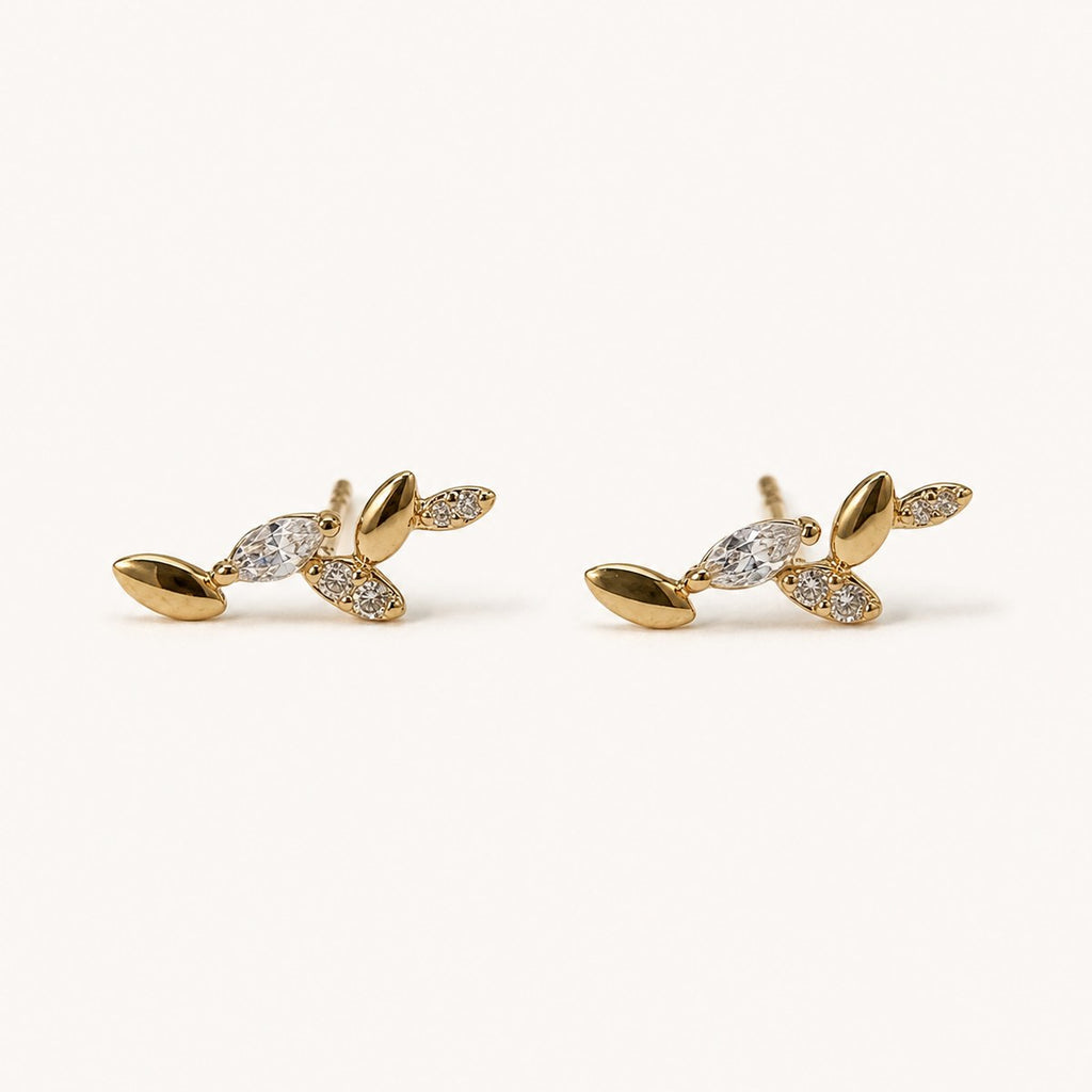 14K solid gold crystal leaf branch stud earrings on a warm ivory background
