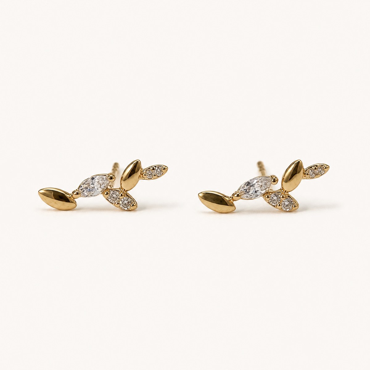 14K solid gold crystal leaf branch stud earrings on a warm ivory background