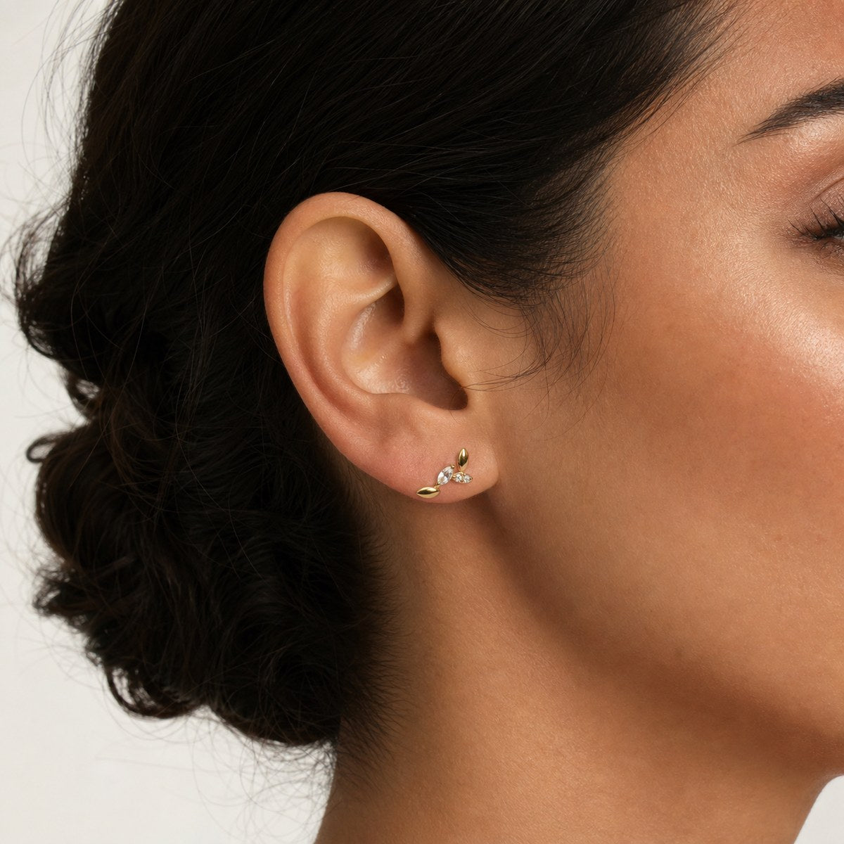 14K solid gold crystal leaf branch stud earrings worn on an ear