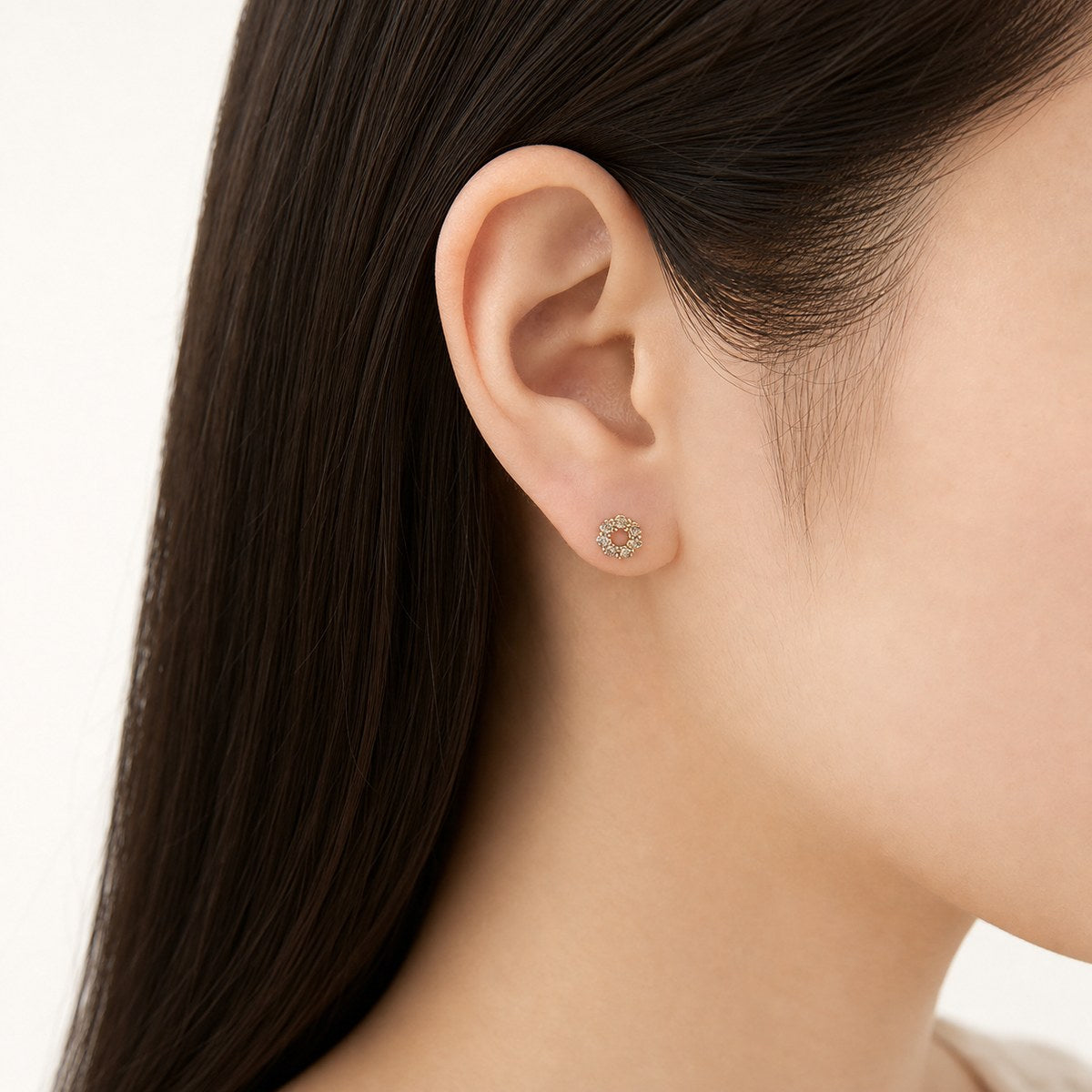14K solid gold floral halo stud earrings worn on an ear
