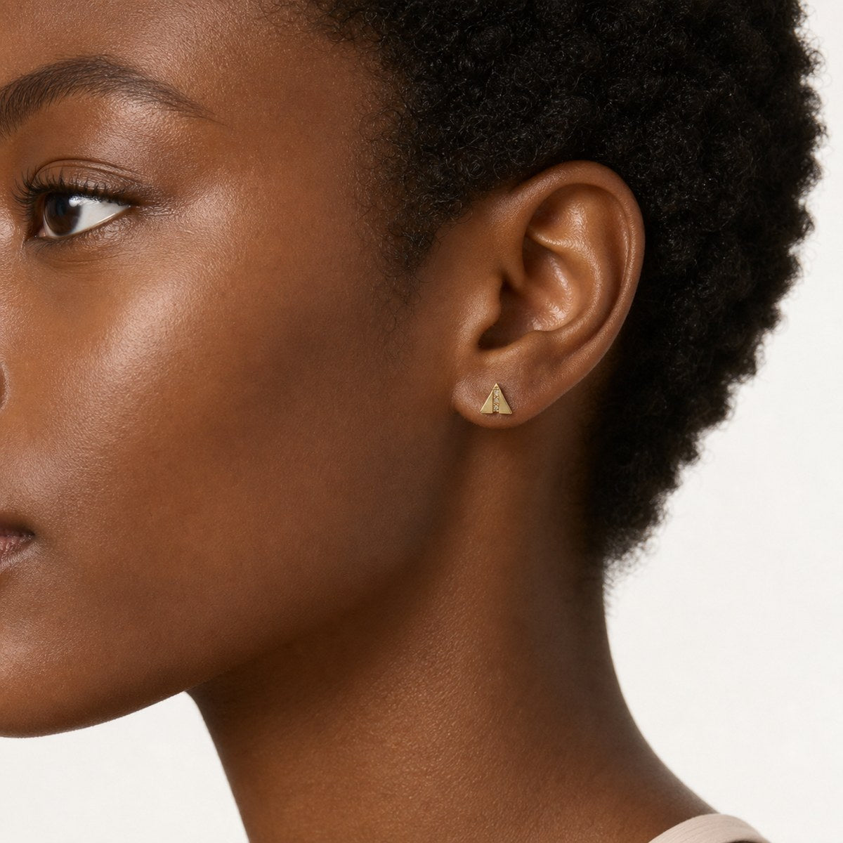 14K solid gold geometric triangle stud earrings worn on an ear
