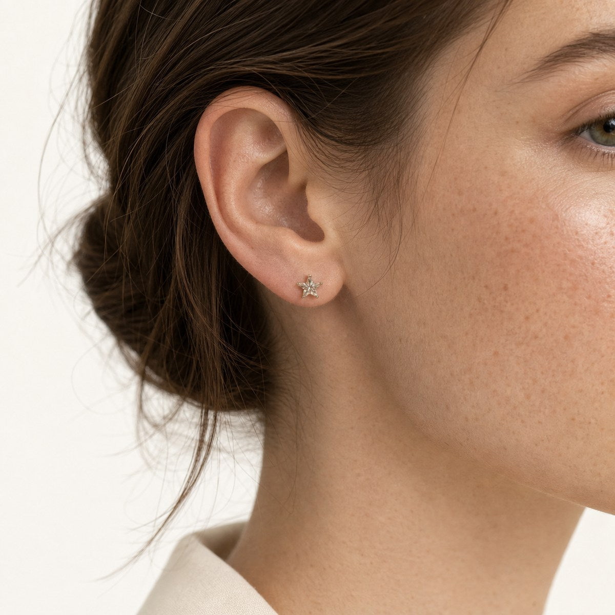 14K solid gold crystal star stud earrings worn on an ear