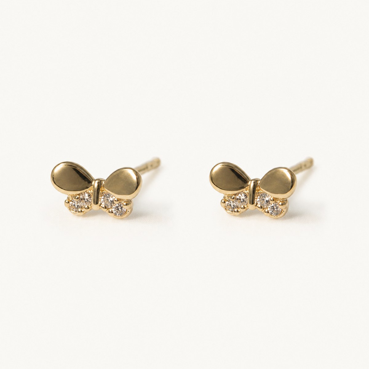 14K solid gold crystal bow stud earrings on a warm ivory background
