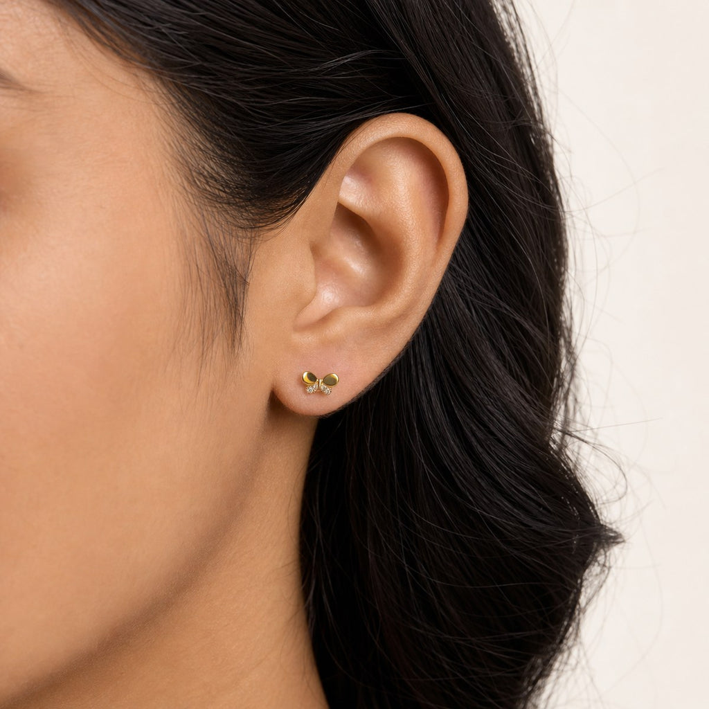 14K solid gold crystal bow stud earrings worn on an ear