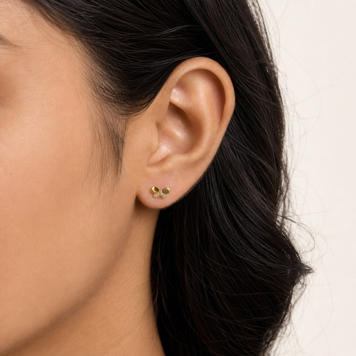 14K solid gold crystal bow stud earrings worn on an ear