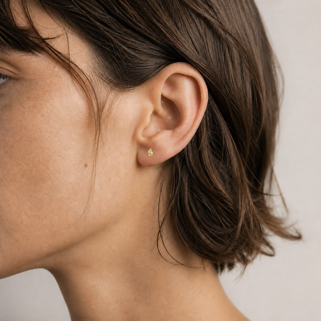 14K solid gold minimal crescent stud earrings worn on an ear