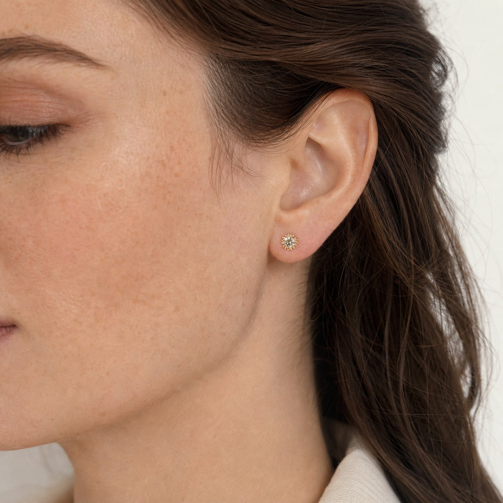 14K solid gold sunflower halo stud earrings worn on an ear