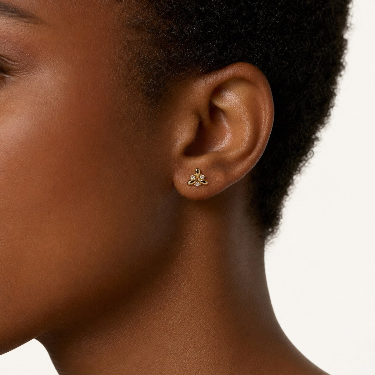 14K solid gold crystal bee stud earrings worn on an ear