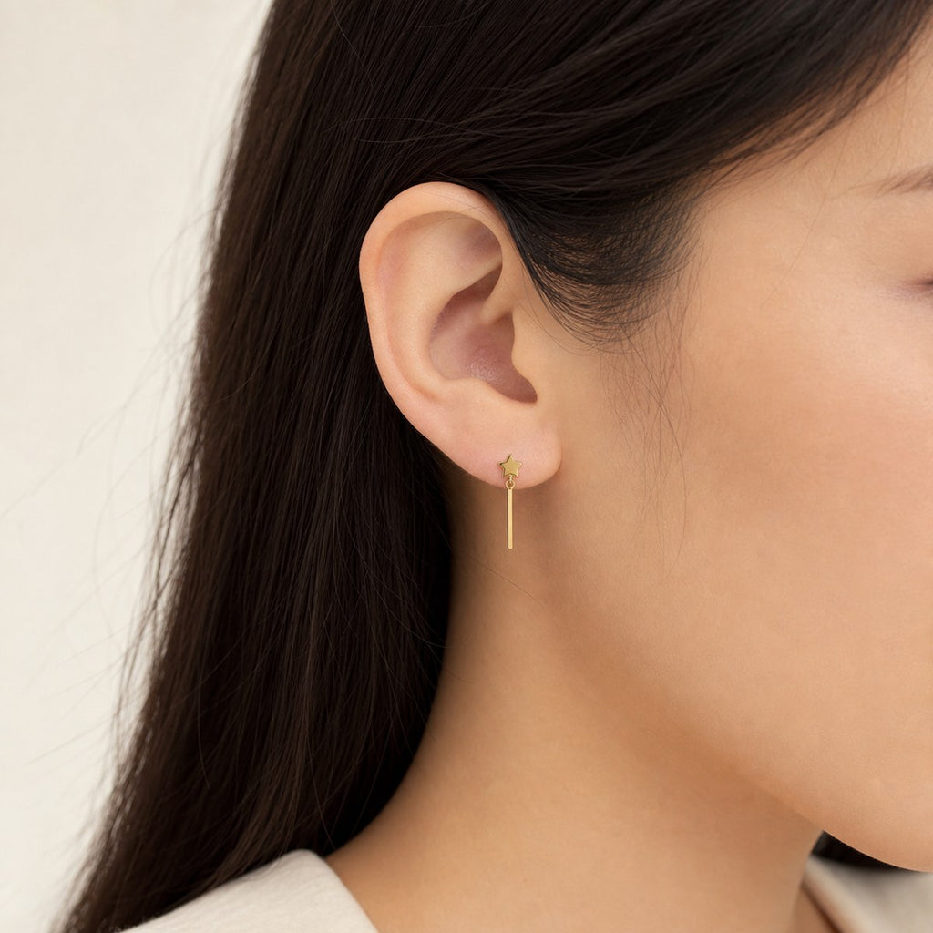 14K solid gold star bar drop stud earrings worn on an ear