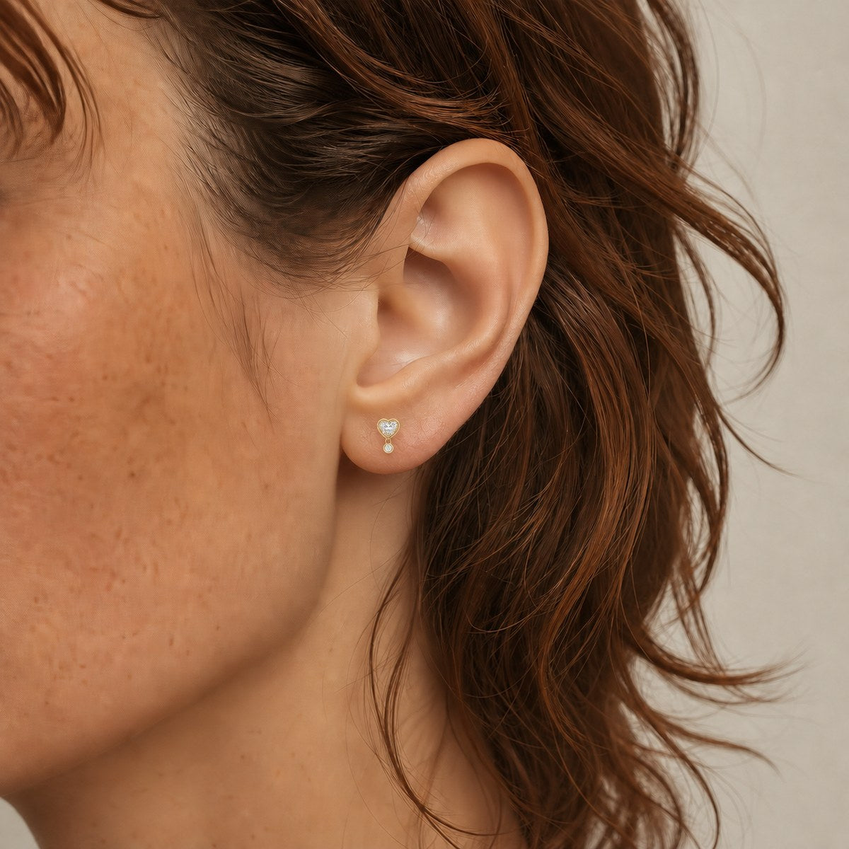 14K solid gold double stone stud earrings worn on an ear