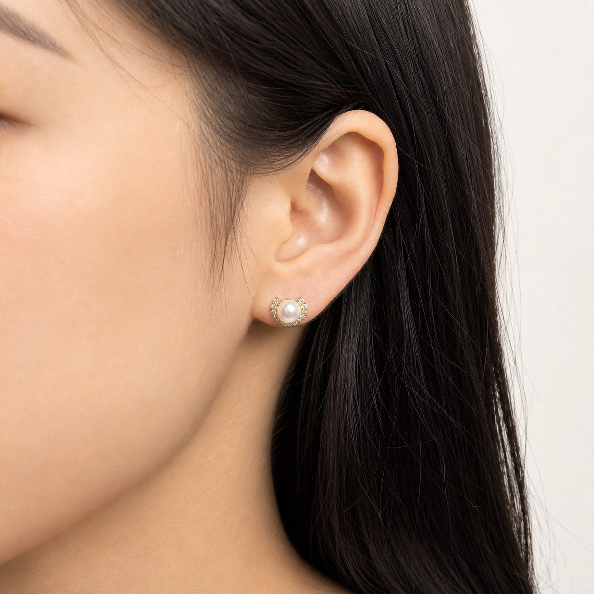 14K solid gold pearl crescent stud earrings worn on an ear