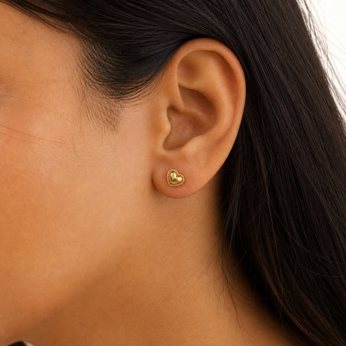 14K solid gold beaded heart stud earrings worn on an ear