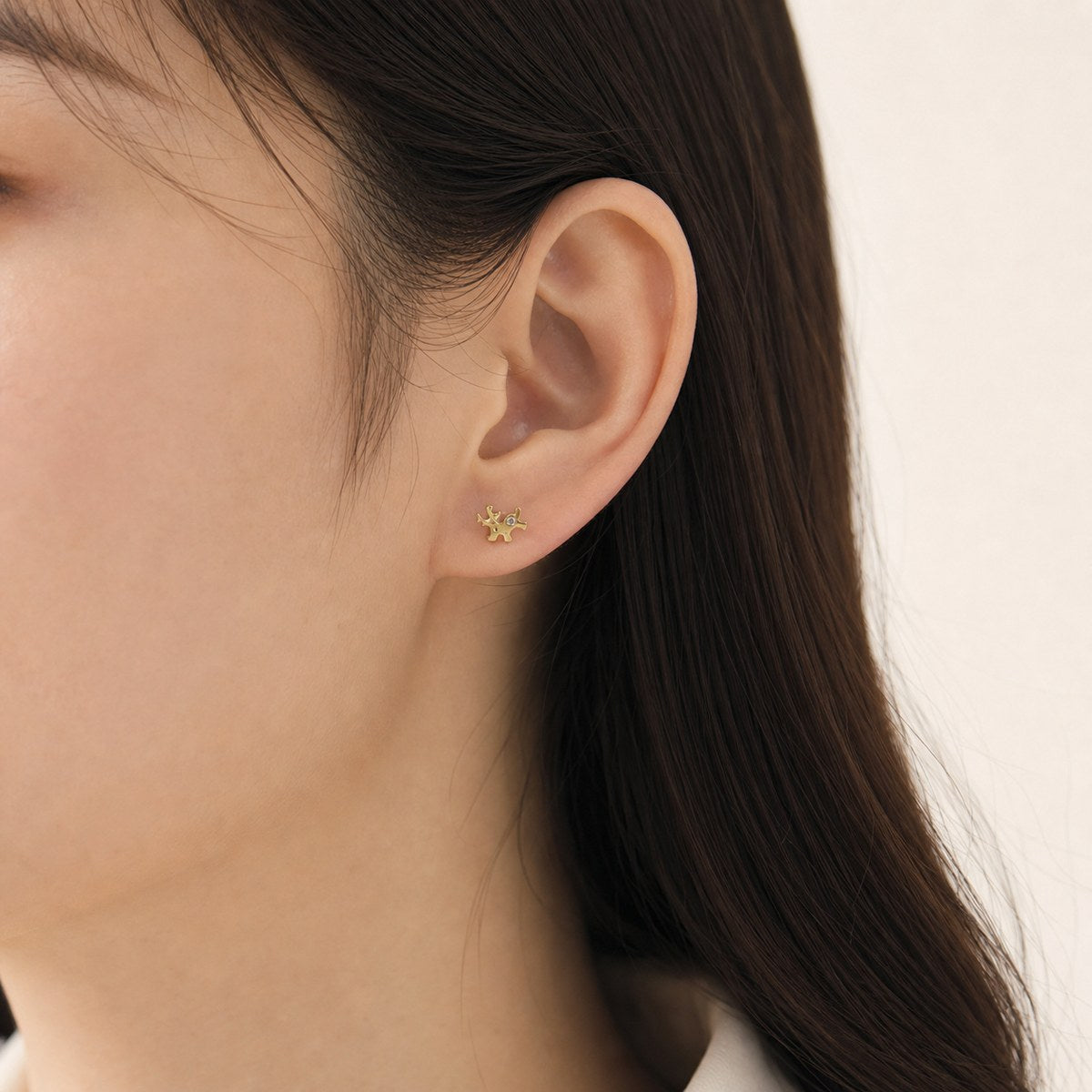 14K solid gold petite antler stud earrings worn on an ear