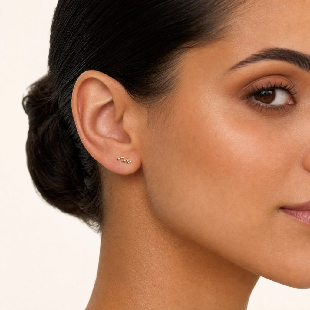 14K solid gold crystal wave climber stud earrings worn on an ear