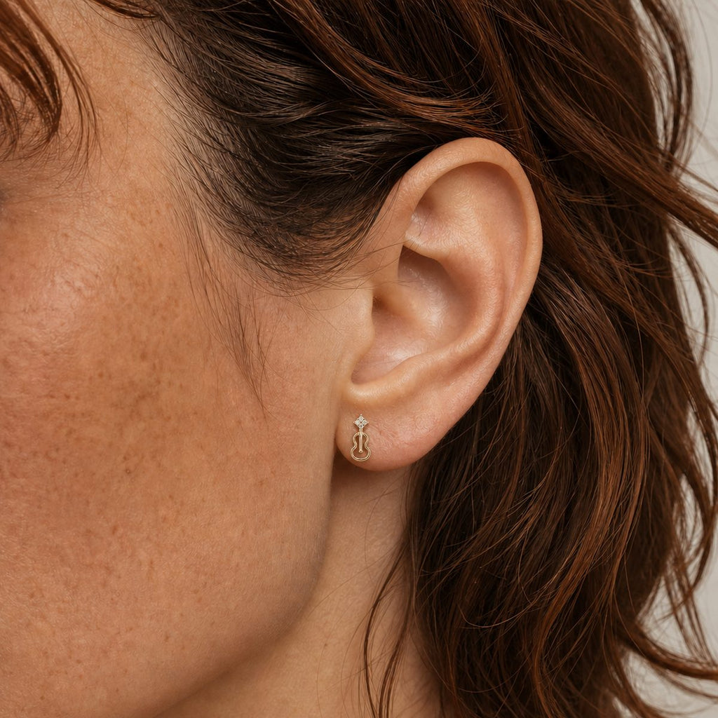 14K solid gold abstract flame stud earrings worn on an ear