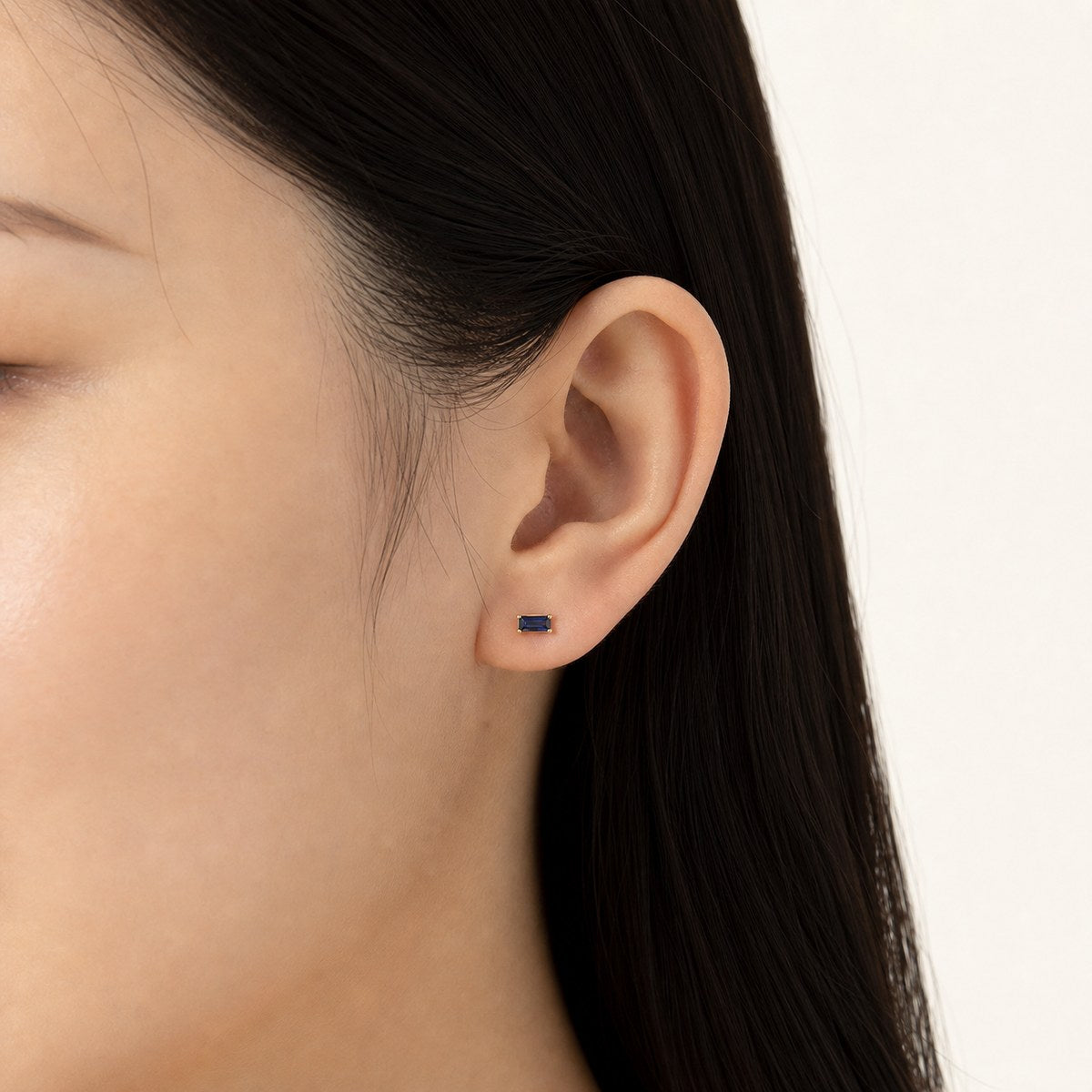 14K solid gold black emerald cut stud earrings worn on an ear