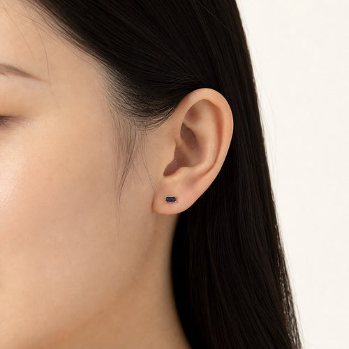 14K solid gold black emerald cut stud earrings worn on an ear