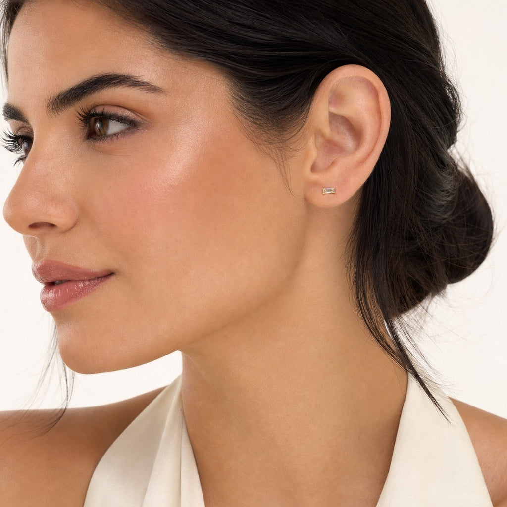 14K solid gold clear baguette stud earrings worn on an ear