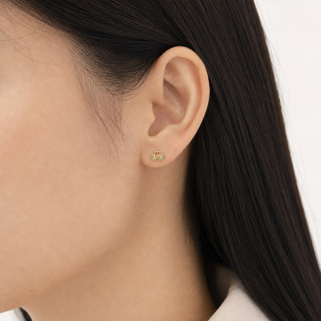 14K solid gold playful car stud earrings worn on an ear