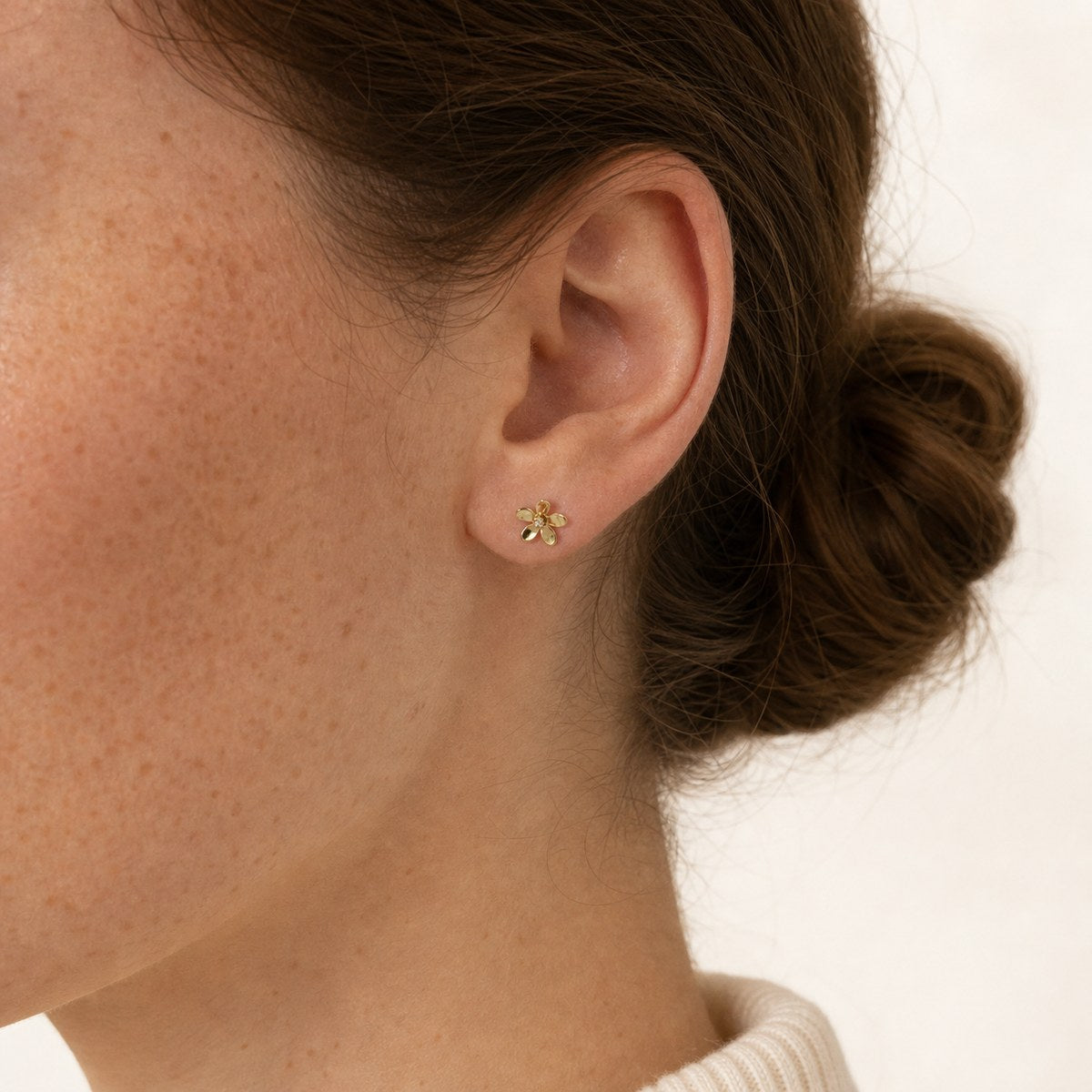 14K solid gold open petal flower stud earrings worn on an ear