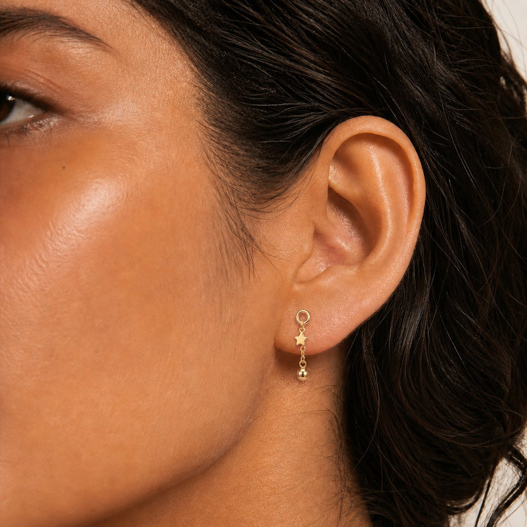 14K solid gold star ball chain drop earrings worn on an ear