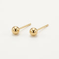 14K solid gold polished gold ball stud earrings on a warm ivory background