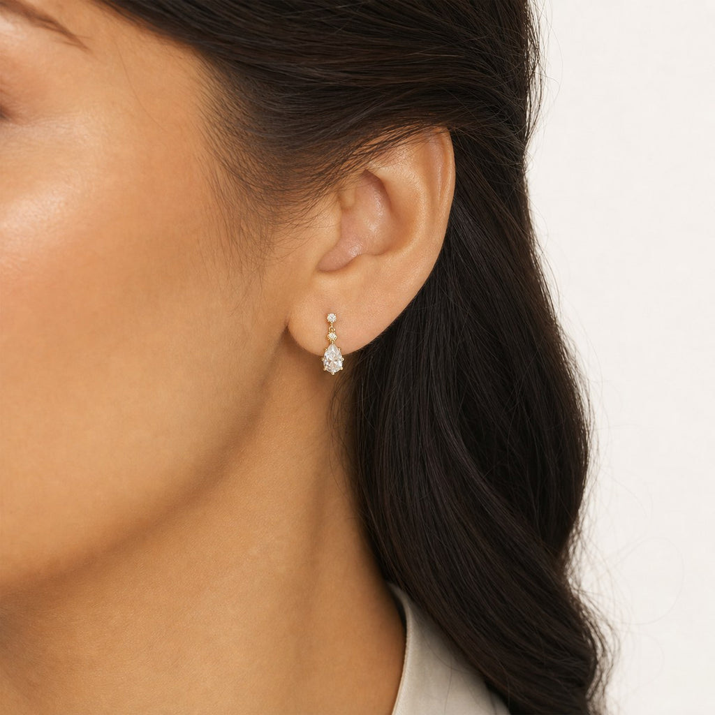 14K solid gold bezel teardrop drop stud earrings worn on an ear