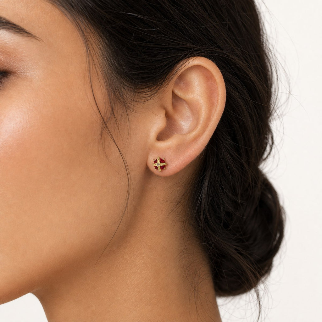 14K solid gold ruby cross stud earrings worn on an ear