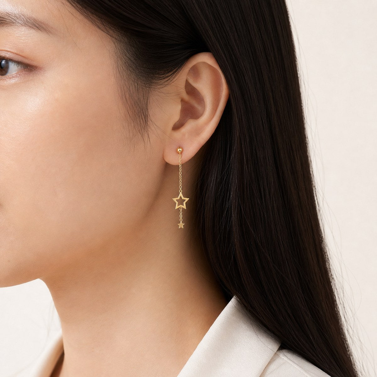14K solid gold double star stud earrings worn on an ear