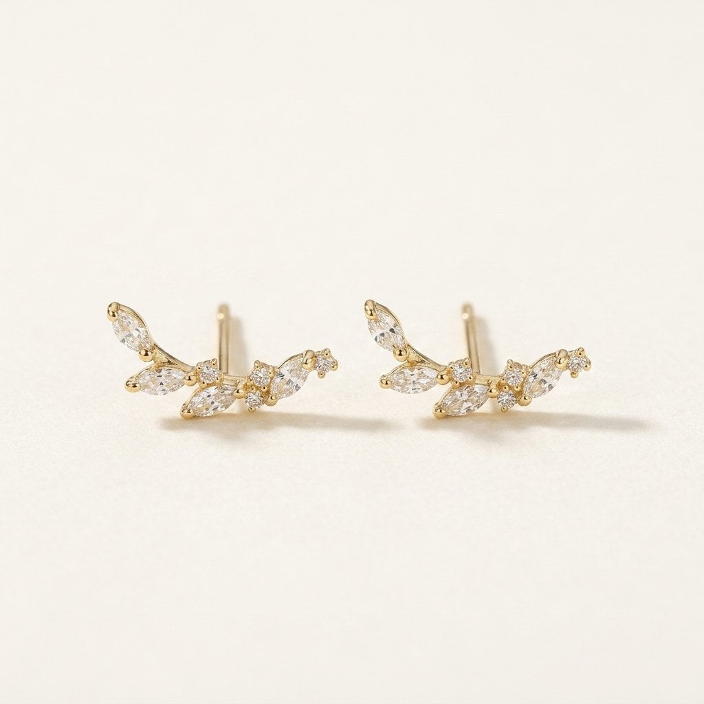 14K solid gold crystal leaf climber stud earrings on a warm ivory background