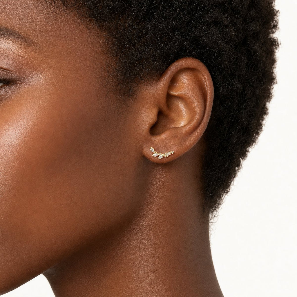 14K solid gold crystal leaf climber stud earrings worn on an ear