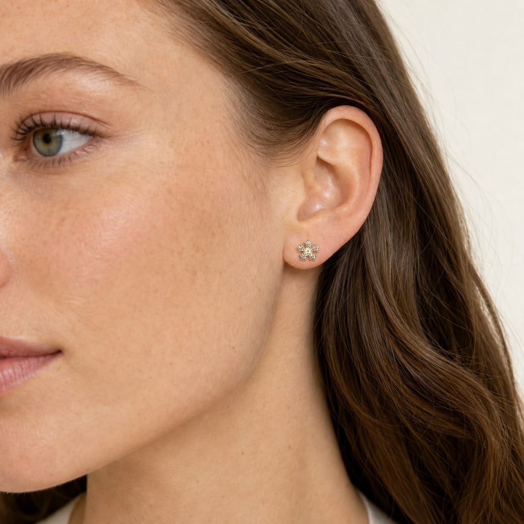 14K solid gold crystal daisy stud earrings worn on an ear