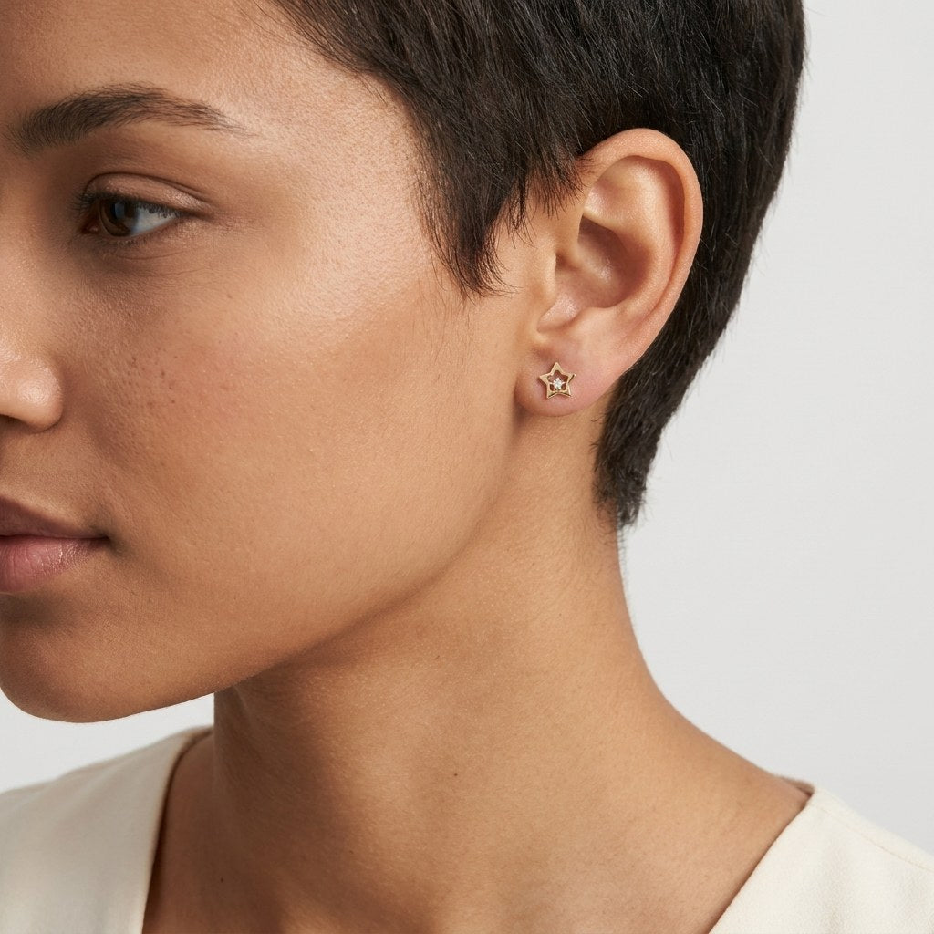 14K solid gold outline star stud earrings worn on an ear