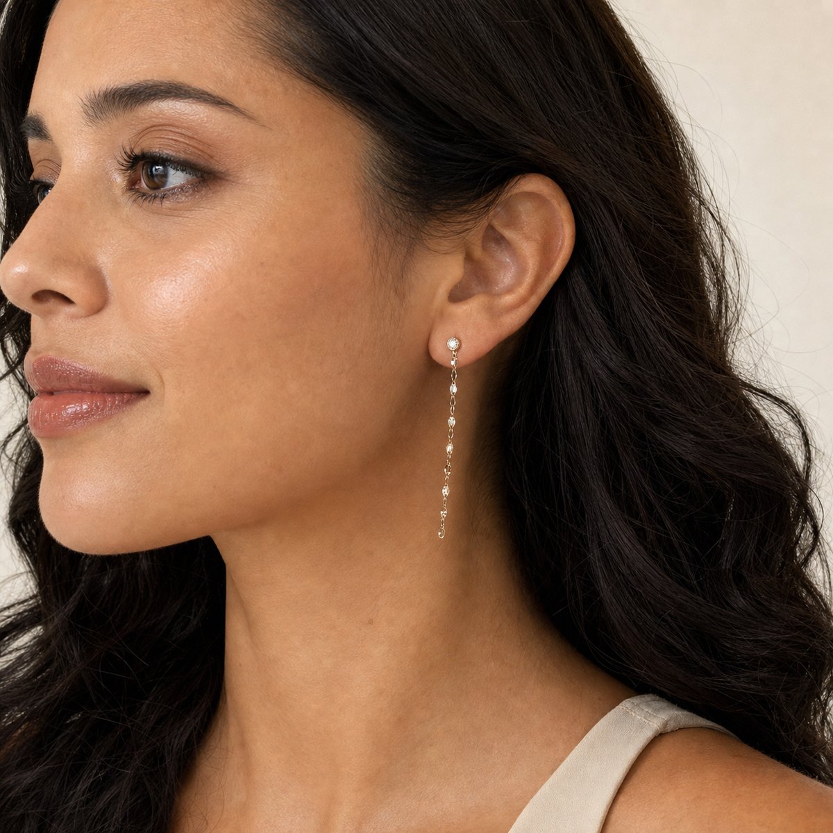 14K solid gold bezel stone chain drop earrings worn on an ear