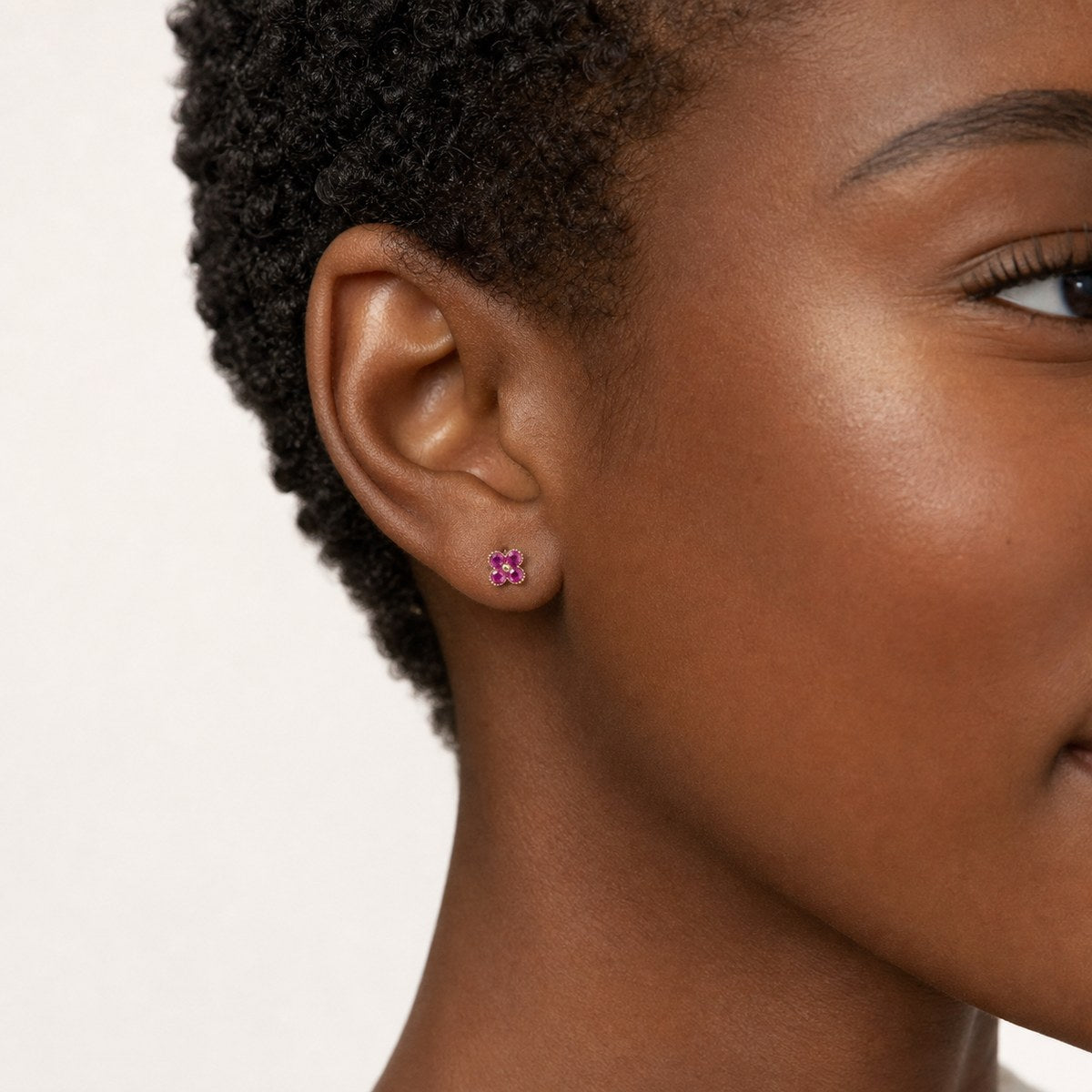 14K solid gold ruby clover stud earrings worn on an ear