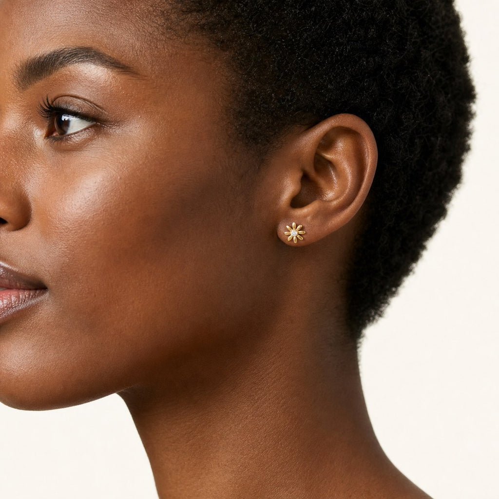 14K solid gold open daisy stud earrings worn on an ear