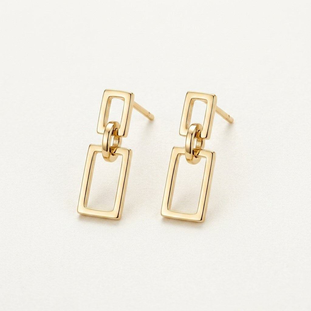 14K solid gold geometric rectangle drop stud earrings on a warm ivory background
